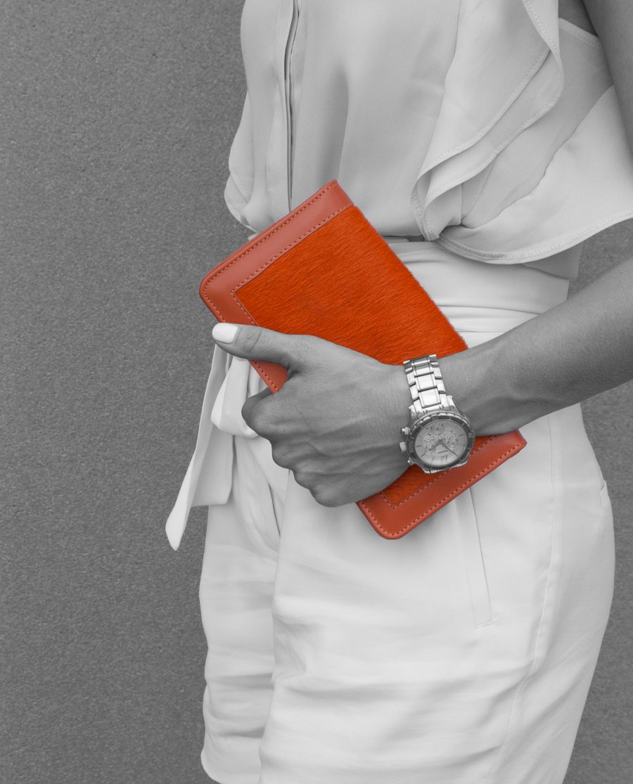 Orange Calf Hair Leather Clutch Bag in woman hands staying near wall
